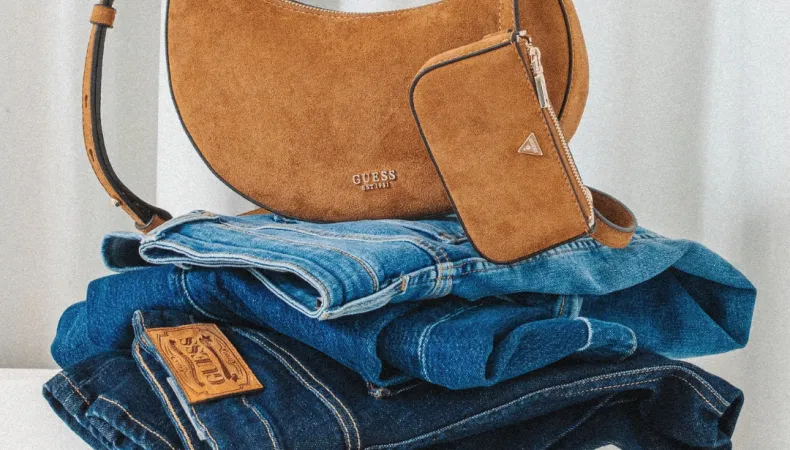 GUESS handbag on top of a stack of jeans